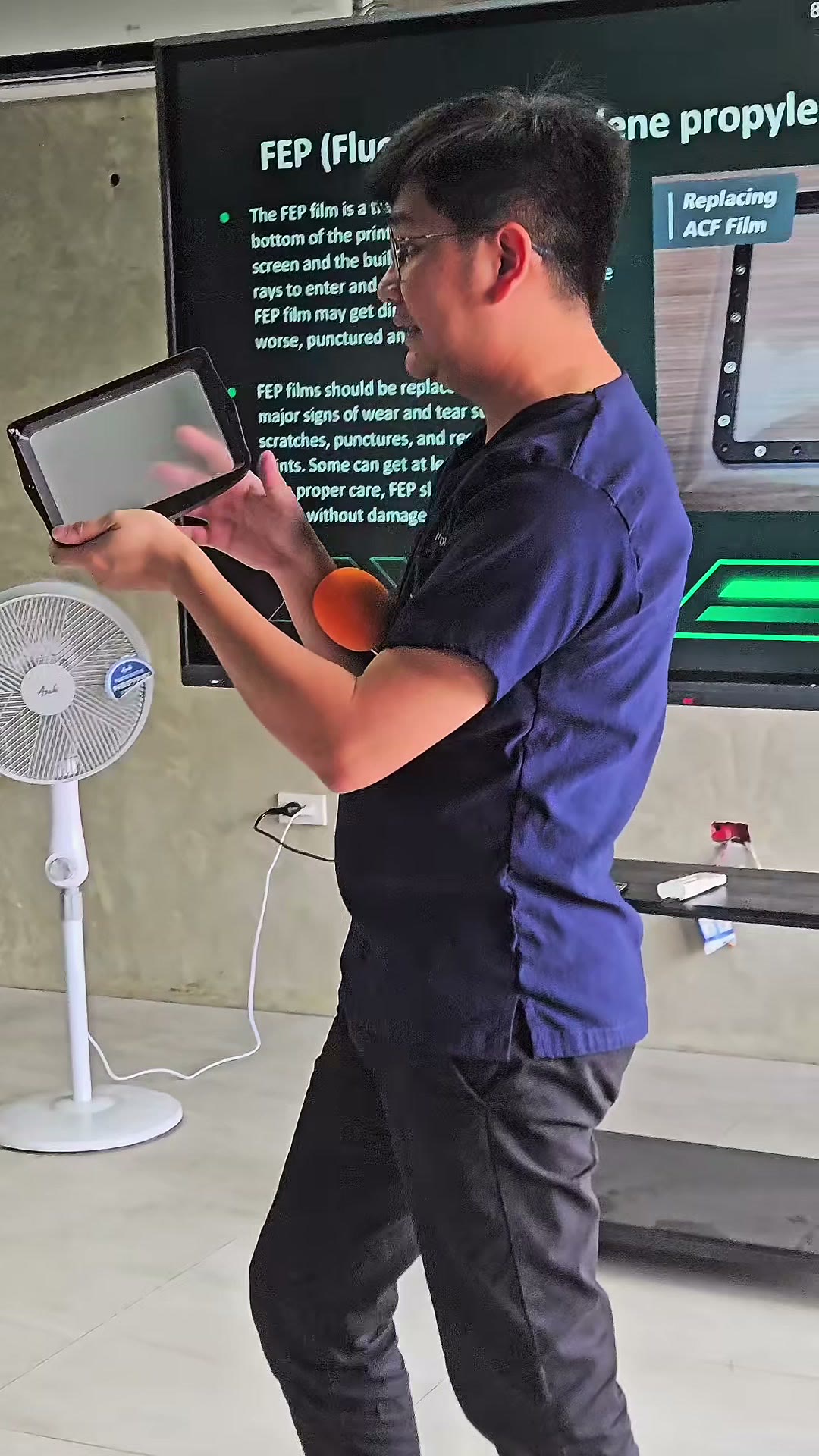 Instructor holding a build plate beside a slide on FEP film