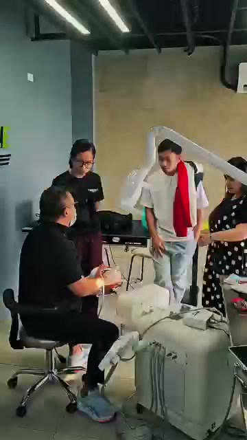 The instructor seated at a simulator with trainees gathered around