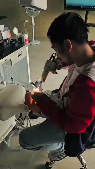 A trainee with a handpiece at the phantom head station