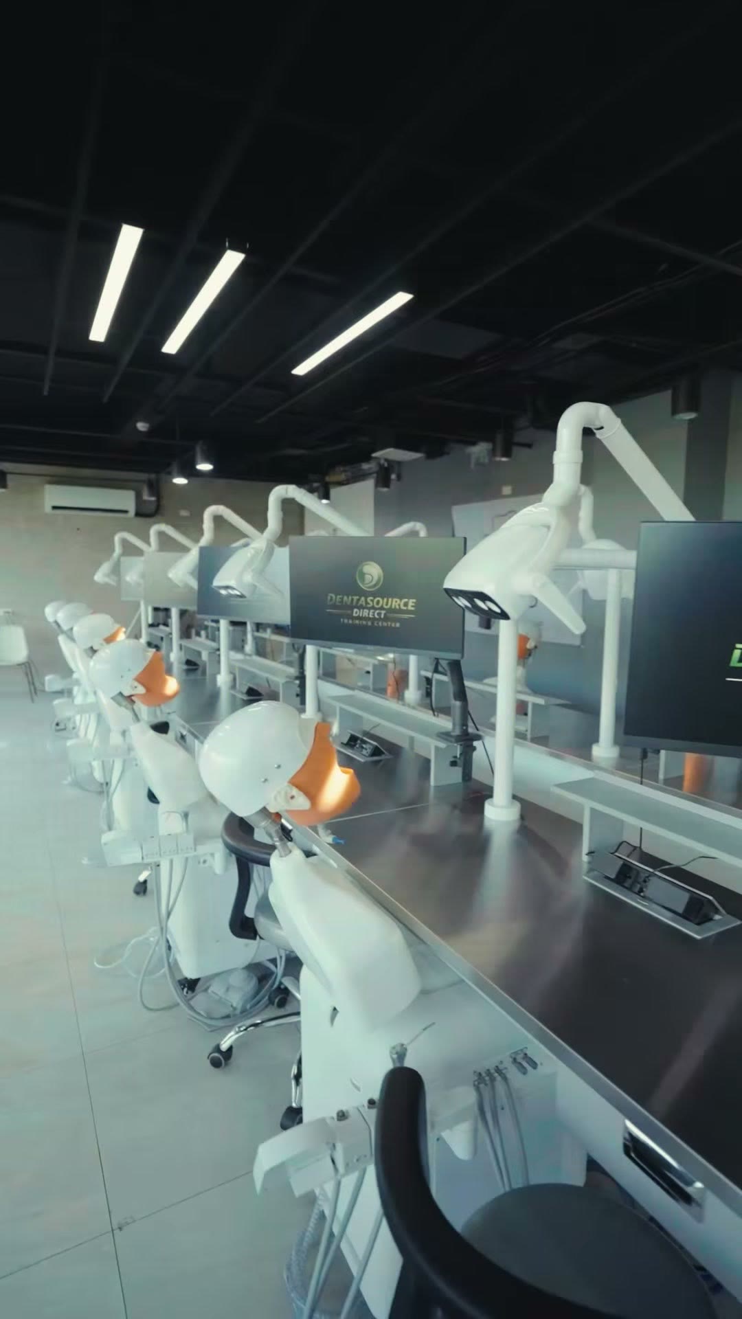 The simulator row at the DentaSource Direct Training Center, each station with its own LED operating light and screen