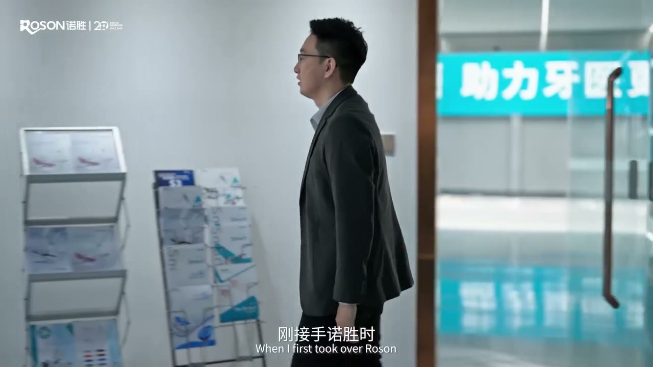 George Chen walking past ROSON's mission wall — "helping dentists excel"