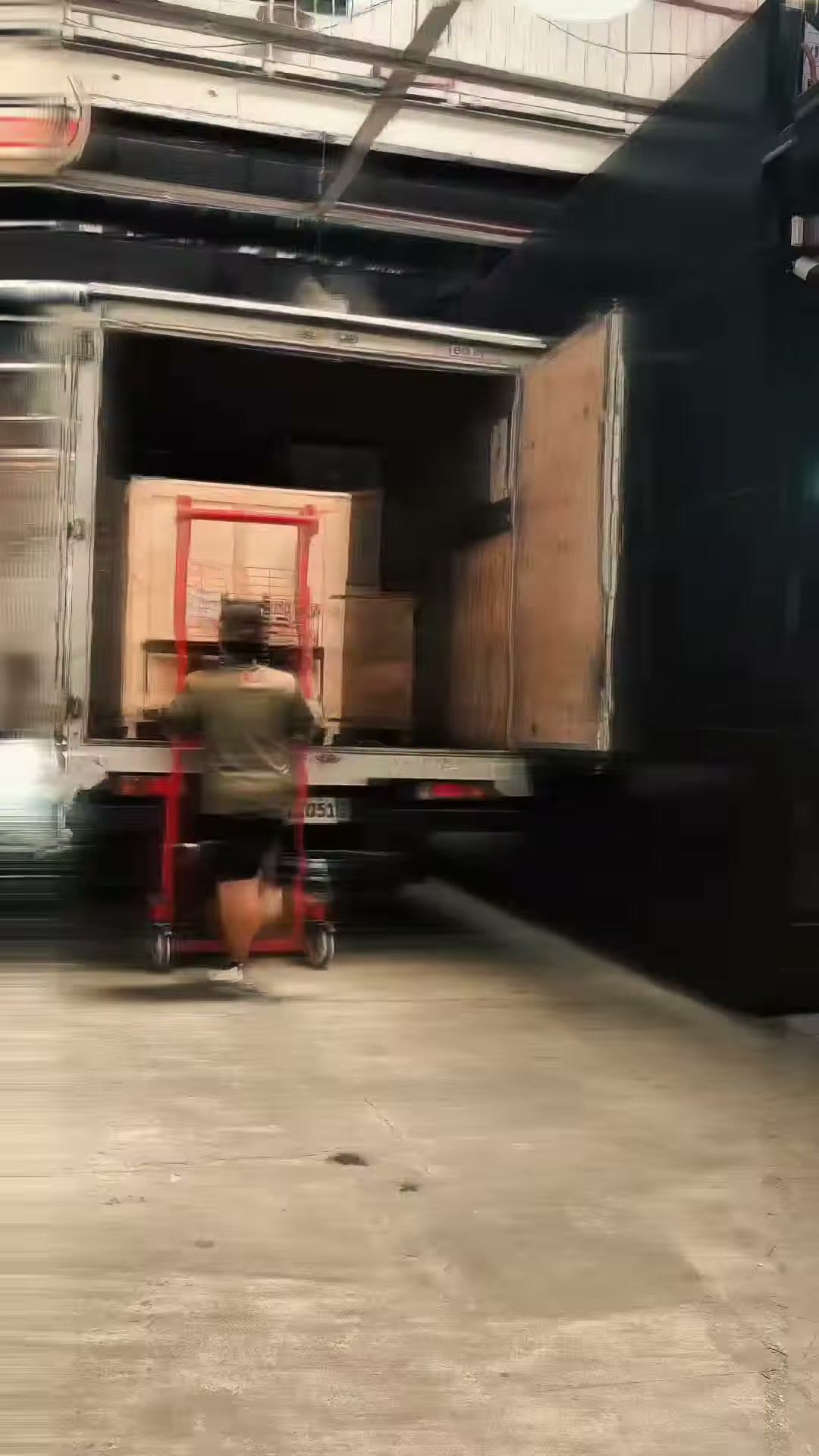 A pallet jack pulling a crate out of the truck