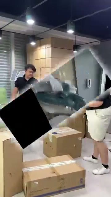 Team lifting a wrapped chair unit among stacked cartons