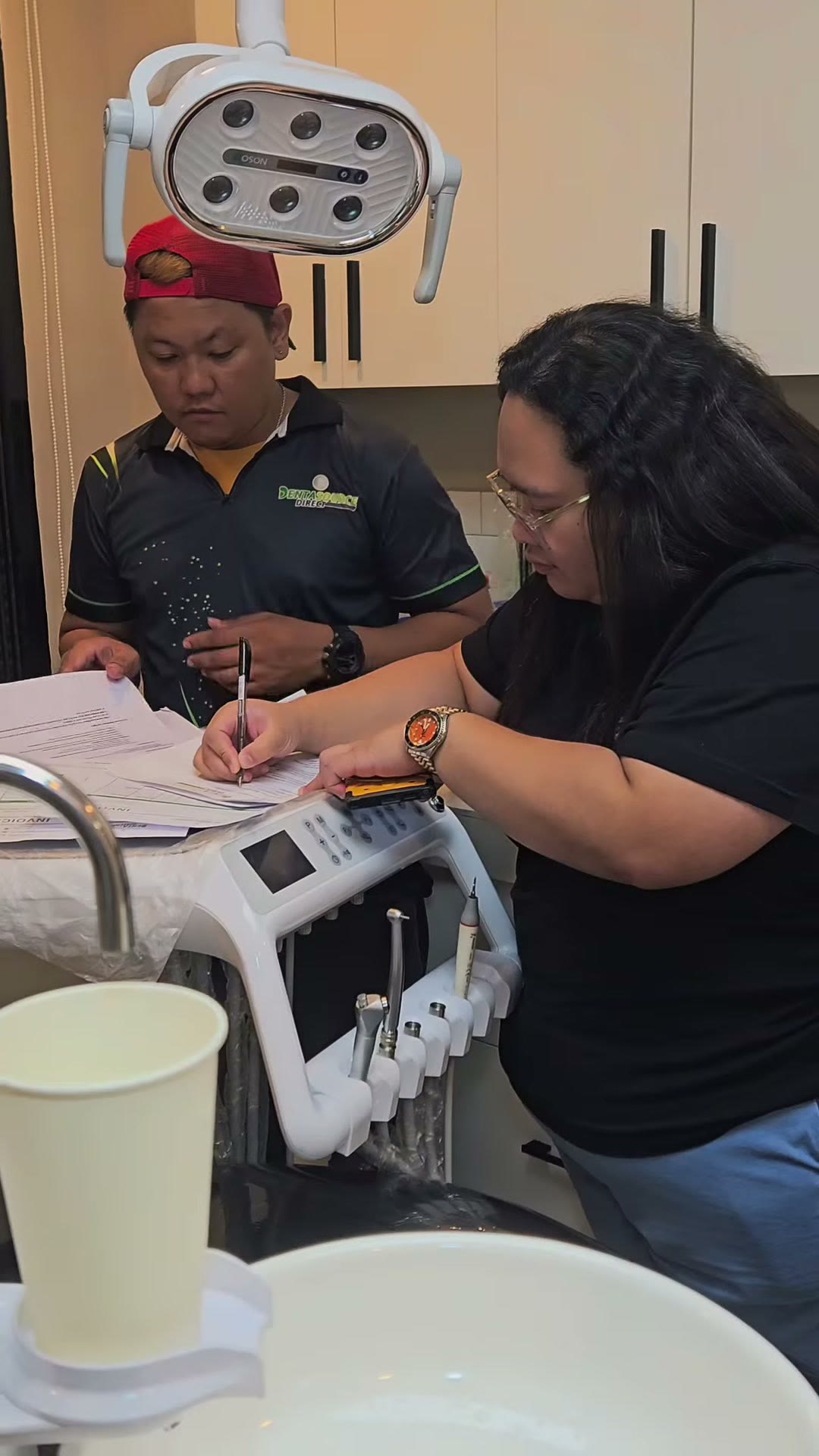 The dentist signing the handover documents under the LED light