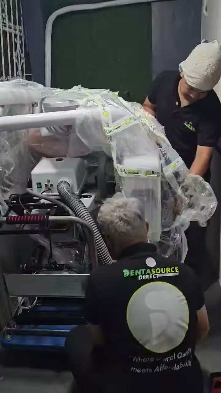 Technicians easing the wrapped unit through the doorway