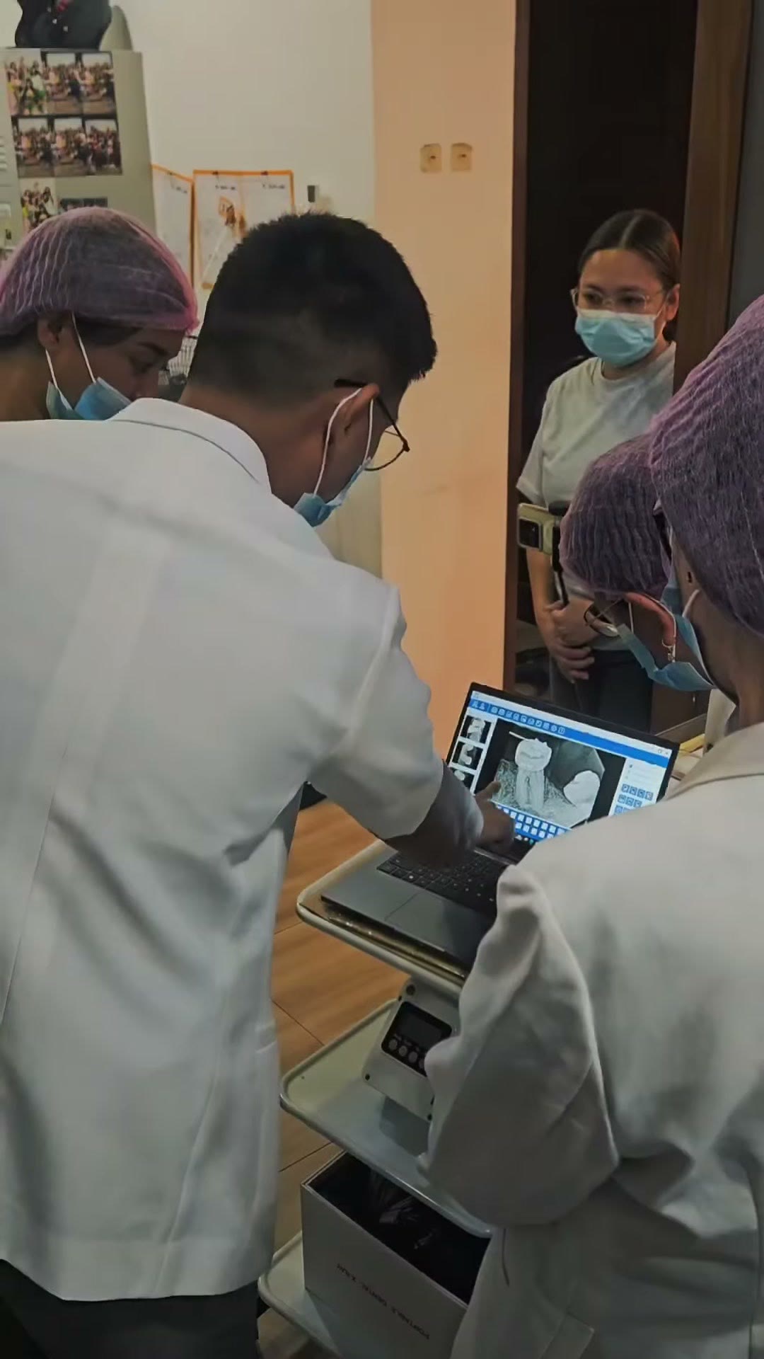 The instructor and a trainee reviewing the scan on a laptop with the cohort watching