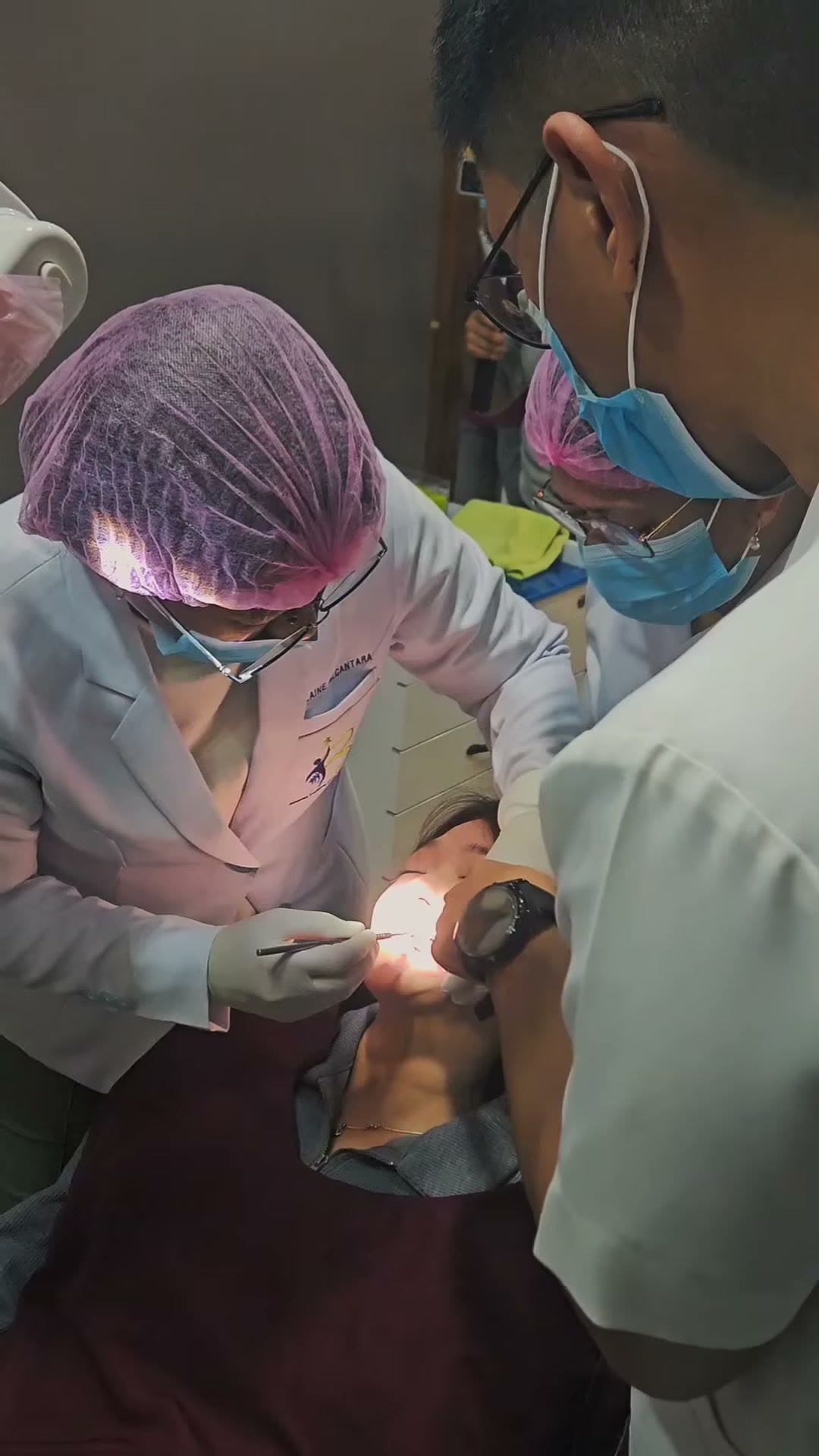 The instructor guiding a trainee placing a mini screw on a patient
