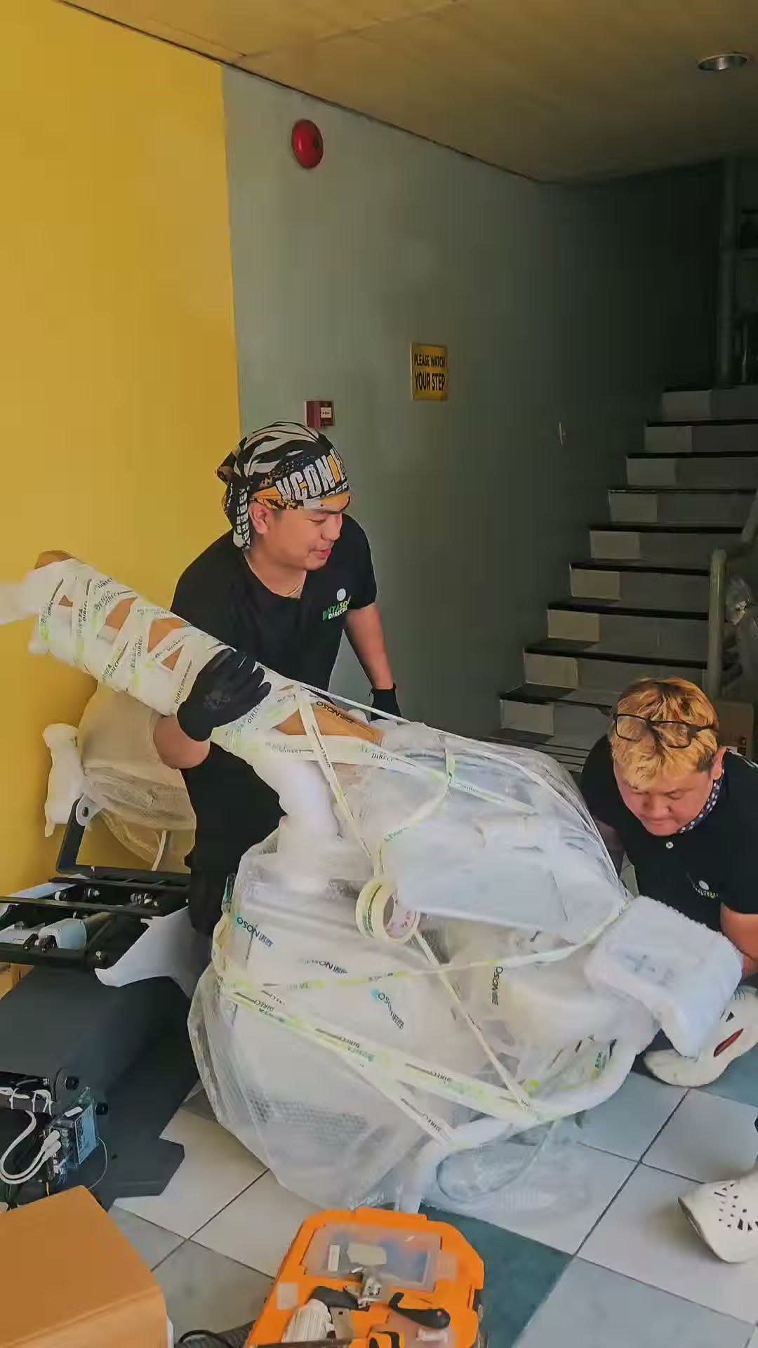 Two technicians unwrapping the chair in the clinic stairwell