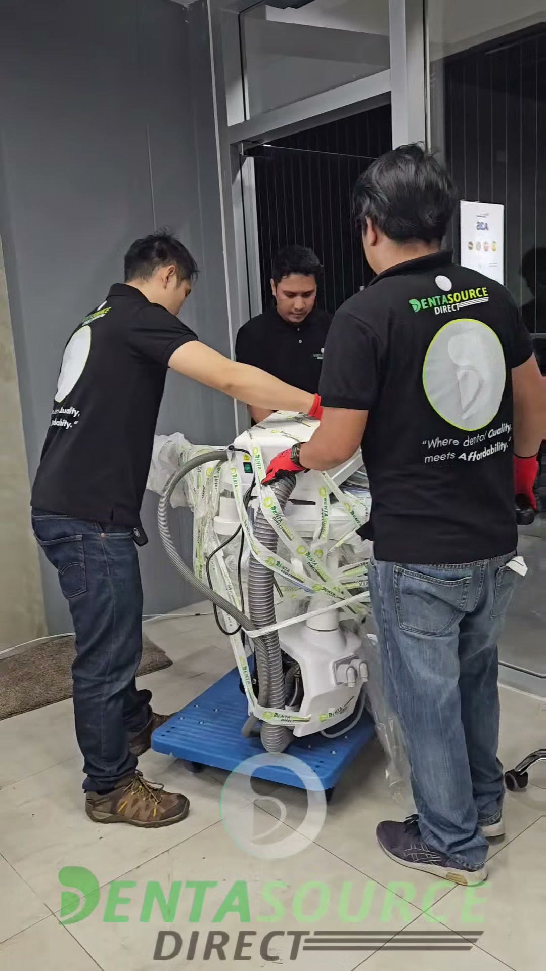 Three technicians steering a wrapped unit on a dolly