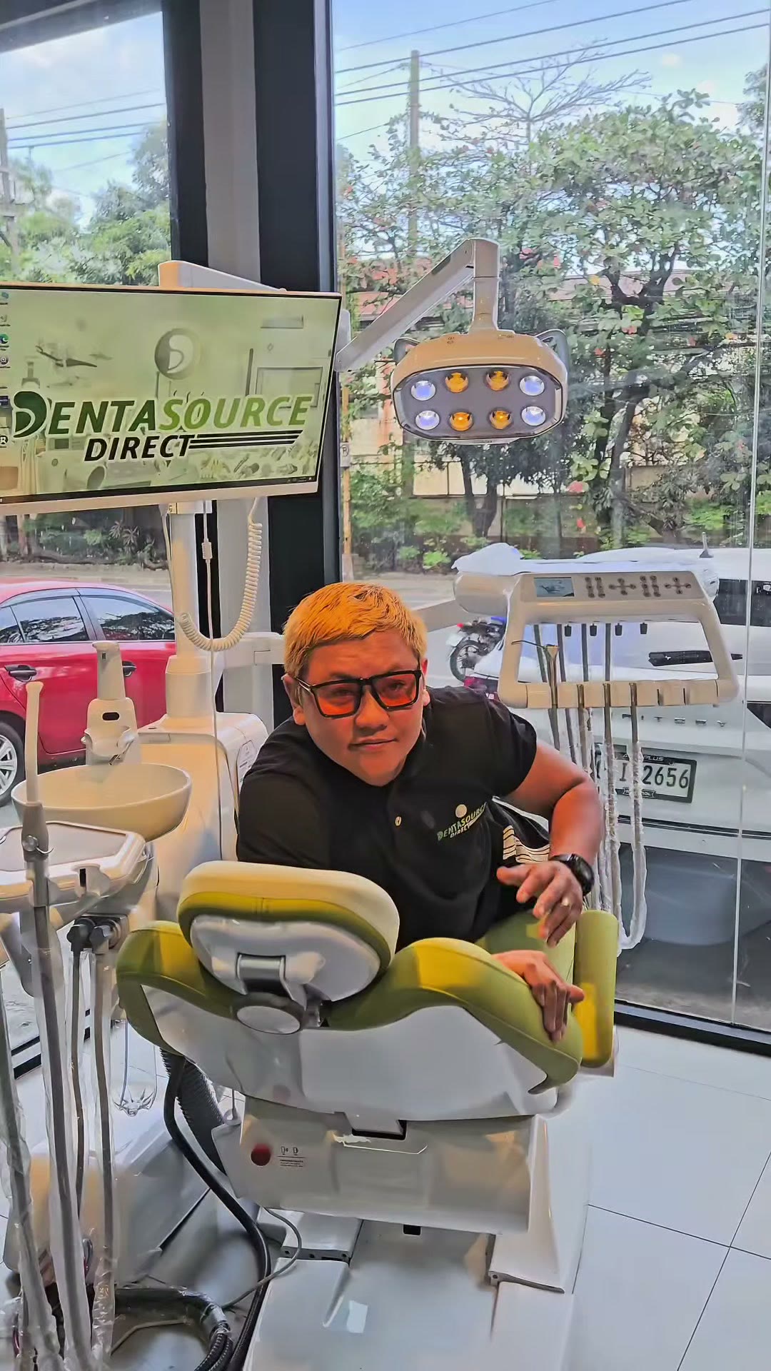 Our staff beside a chair under the LED light and the DentaSource sign